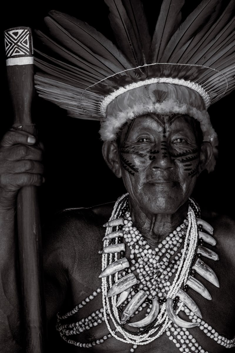 Black and white portrait of an indigenous elder wearing traditional headdress and necklaces in Manaus, Brazil.