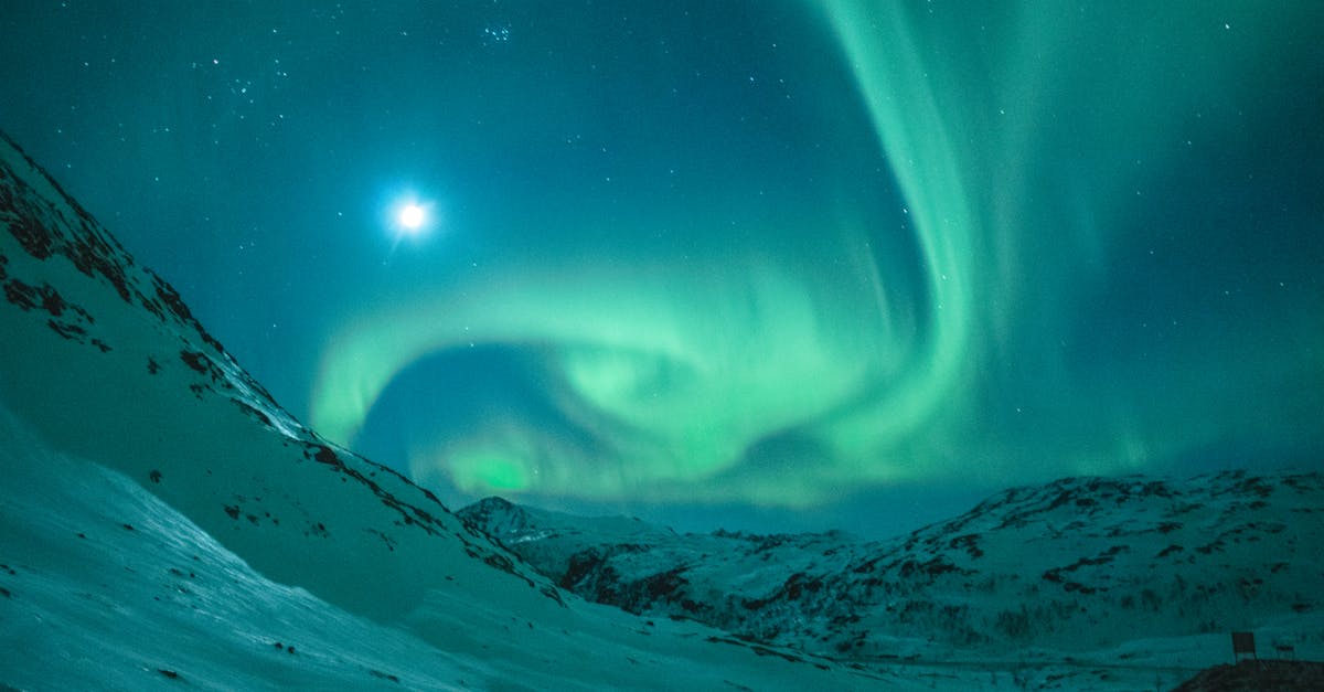 Dazzling aurora borealis illuminating the night sky above a serene snowy mountain landscape.