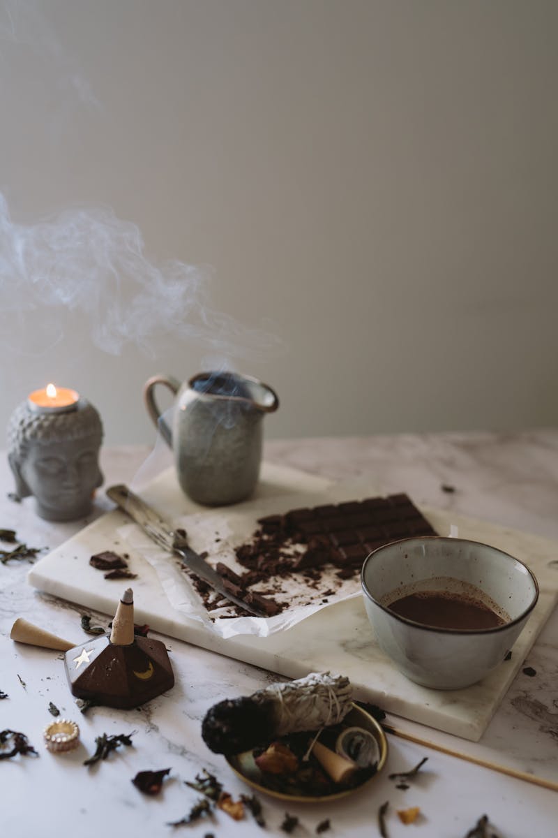 Atmospheric setup with chocolate, incense, and ceramic cups evokes relaxation and mindfulness.